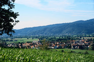 View of a village surrounded by rolling meadows and wooded hills