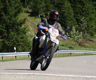 A motorcyclist taking a curve on an uphill stretch