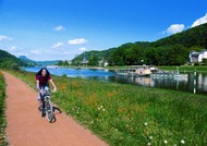 Cyclist on cycle path along the Elbe with steamboat